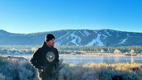 Profiboxer Ronaldo Mancilla joggt auf einer Straße in Big Bear Lake, Kalifornien, mit dem See und den Bergen im Hintergrund.