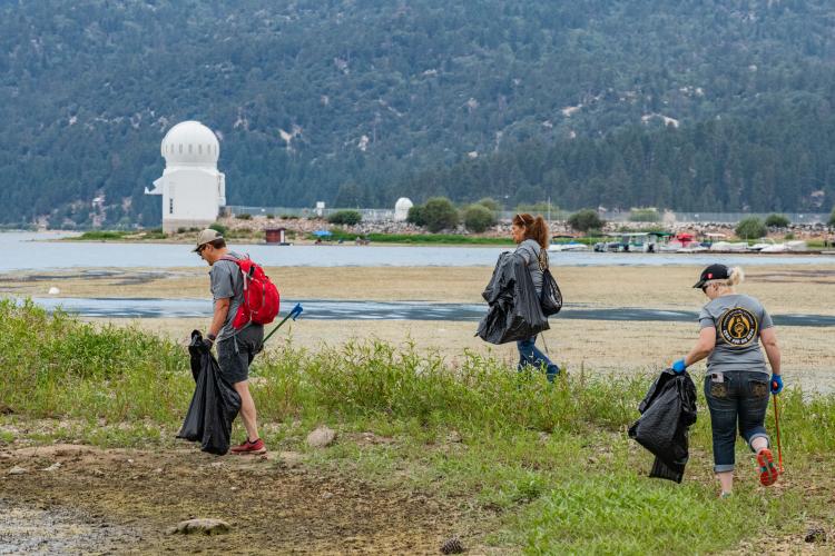 Freiwillige Helfer sammeln während einer Aufräumaktion von Care For Big Bear Müll am Ufer des Big Bear Lake ein.