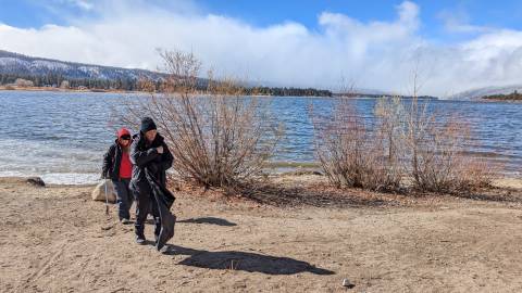 Ein paar warm eingepackte Freiwillige durchsuchen den Big Bear Lakeside nach Müll, den sie im Rahmen der Aktion Care For Big Bear beseitigen.