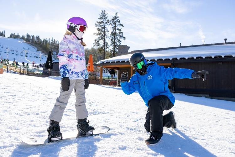 Ein Lehrer führt einen Schüler auf einem Snowboard im Snow Summit Skigebiet in Big Bear Lake, Kalifornien.