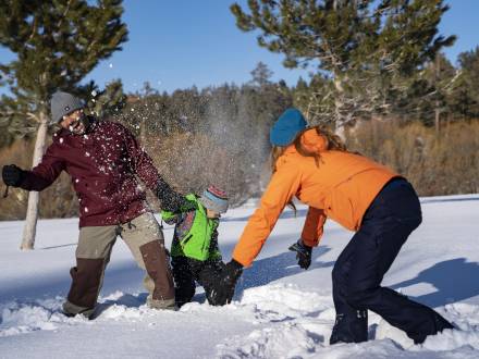 Eine dreiköpfige Familie spielt im Winter am Big Bear Lake im Schnee.