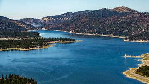 Ein Luftbild des Big Bear Lake. Es ist ein sonniger Tag mit klarem, blauem Himmel und grünen Kiefernwäldern rund um den blauen See.