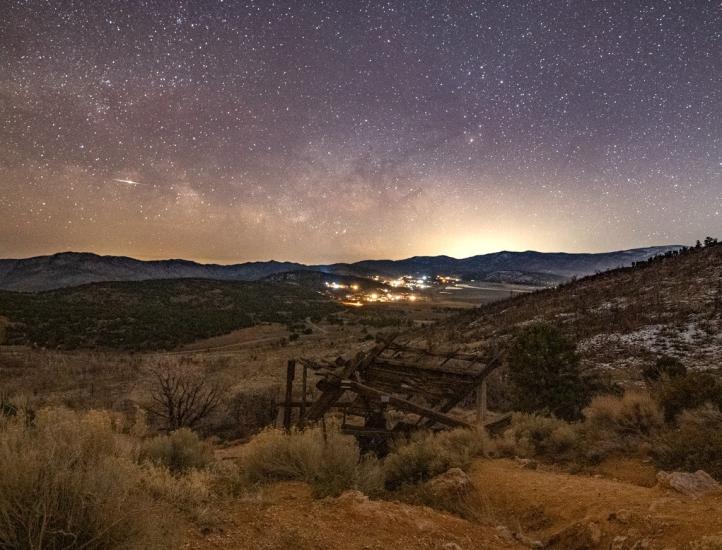 Ein Bild der Sterne und der Milchstraße am Nachthimmel über Big Bear. Im Vordergrund befindet sich ein alter Bergbauschacht.