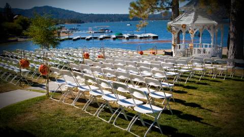 Reihen weißer Stühle und ein Hochzeitsaltar unter einem Pavillon stehen am Seeufer des Big Bear Lake.