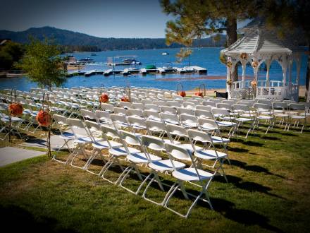 Reihen weißer Stühle und ein Hochzeitsaltar unter einem Pavillon stehen am Seeufer des Big Bear Lake.