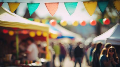 Ein unscharfer Jahrmarkt mit einfachen Verkaufsständen und Menschen, die im Hintergrund herumlaufen