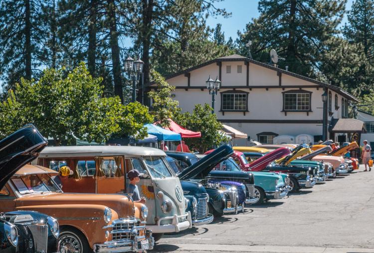 Glänzende und farbenfrohe Oldtimer füllen einen Parkplatz für den Big Bear Lake Fun Run. Die Motorhauben werden für die Zuschauer hochgeklappt.