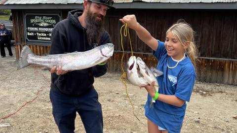 Ein Vater und seine Tochter halten die Forelle, die sie während des 2023 Fishin' For $50K Trout Tournament im Big Bear Lake gefangen haben.
