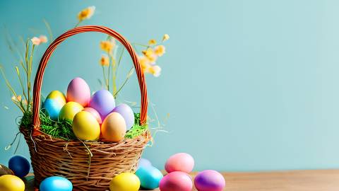 Archivfoto: Ein Osterkorb steht auf einem Tisch mit bunten Eiern und gelben Blumen. Die Wand im Hintergrund ist türkisfarben.