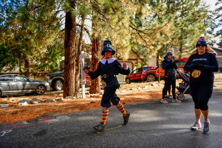 Zwei Läuferinnen, die am Thanksgiving Turkey Trot im Herbst teilnehmen. Die eine Dame trägt ein schwarzes Pilgerkostüm.