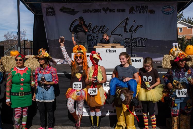 Bei der Siegerehrung während des Thanksgiving Turkey Trot stehen die Läufer in ihren Kostümen vor einer Bühne.