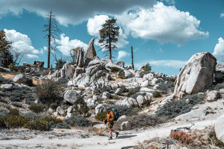eine Person, die an einem sonnigen Tag während der Highlander Adventure-Wanderveranstaltung in Big Bear an Felsformationen vorbeikommt