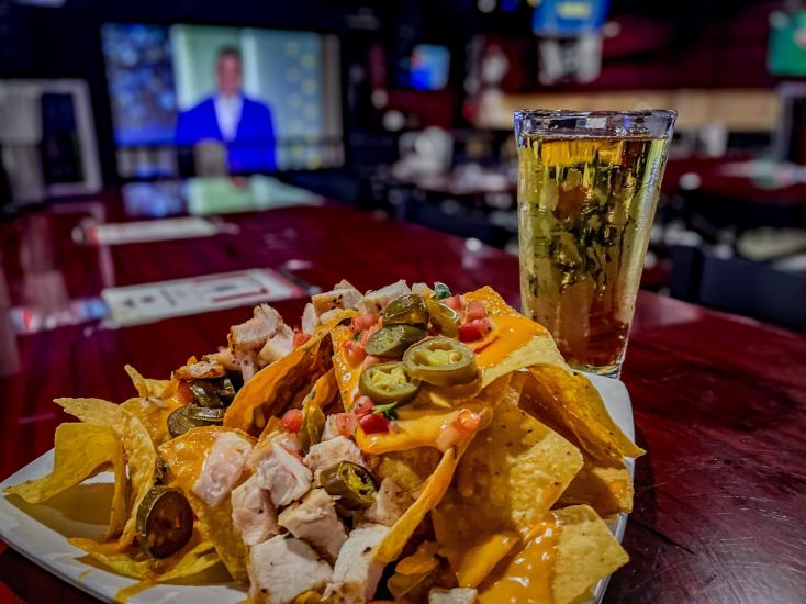 Ein Teller mit Nachos als Vorspeise steht auf einem Tisch mit einem Glas blondem Bier in der Village Sports Bar in Big Bear Lake, CA.