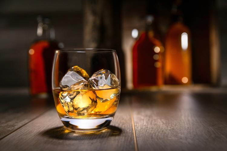 Ein Glas Cognac auf Eis steht auf einem Holztisch.