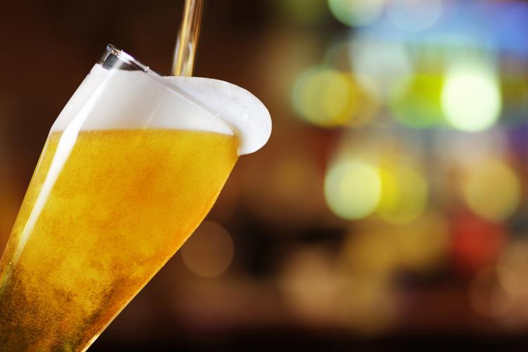 Bernsteinfarbenes Bier fließt in einen Glaskrug und läuft über.