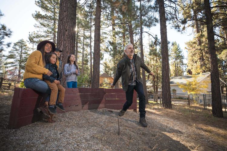 Eine Familie sieht zu, wie der Vater ein Hufeisen in einer Grube im Freien in Big Bear Lake, CA, wirft. Big Bear Unterkunft Unterkünfte.