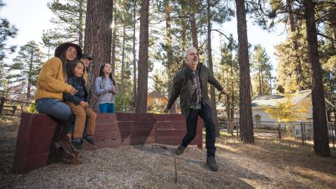 Eine Familie sieht zu, wie der Vater ein Hufeisen in einer Grube im Freien in Big Bear Lake, CA, wirft. Big Bear Unterkunft Unterkünfte.