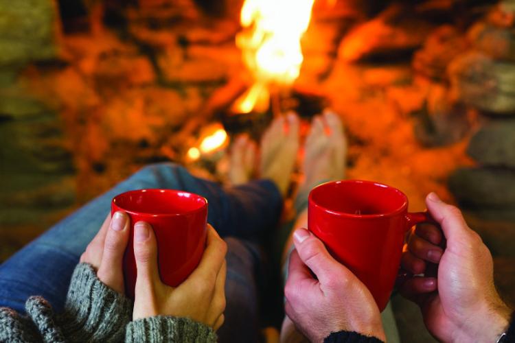 ein paar halten Tassen heißen Kakao am Feuer in Big Bear