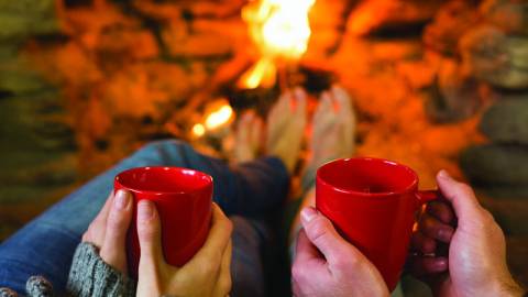 ein paar halten Tassen heißen Kakao am Feuer in Big Bear