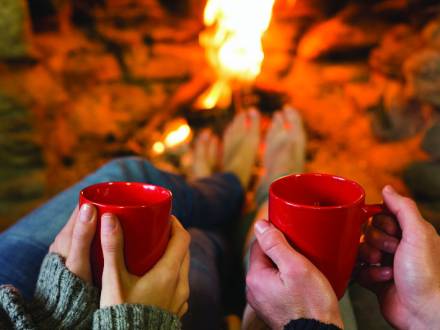 ein paar halten Tassen heißen Kakao am Feuer in Big Bear
